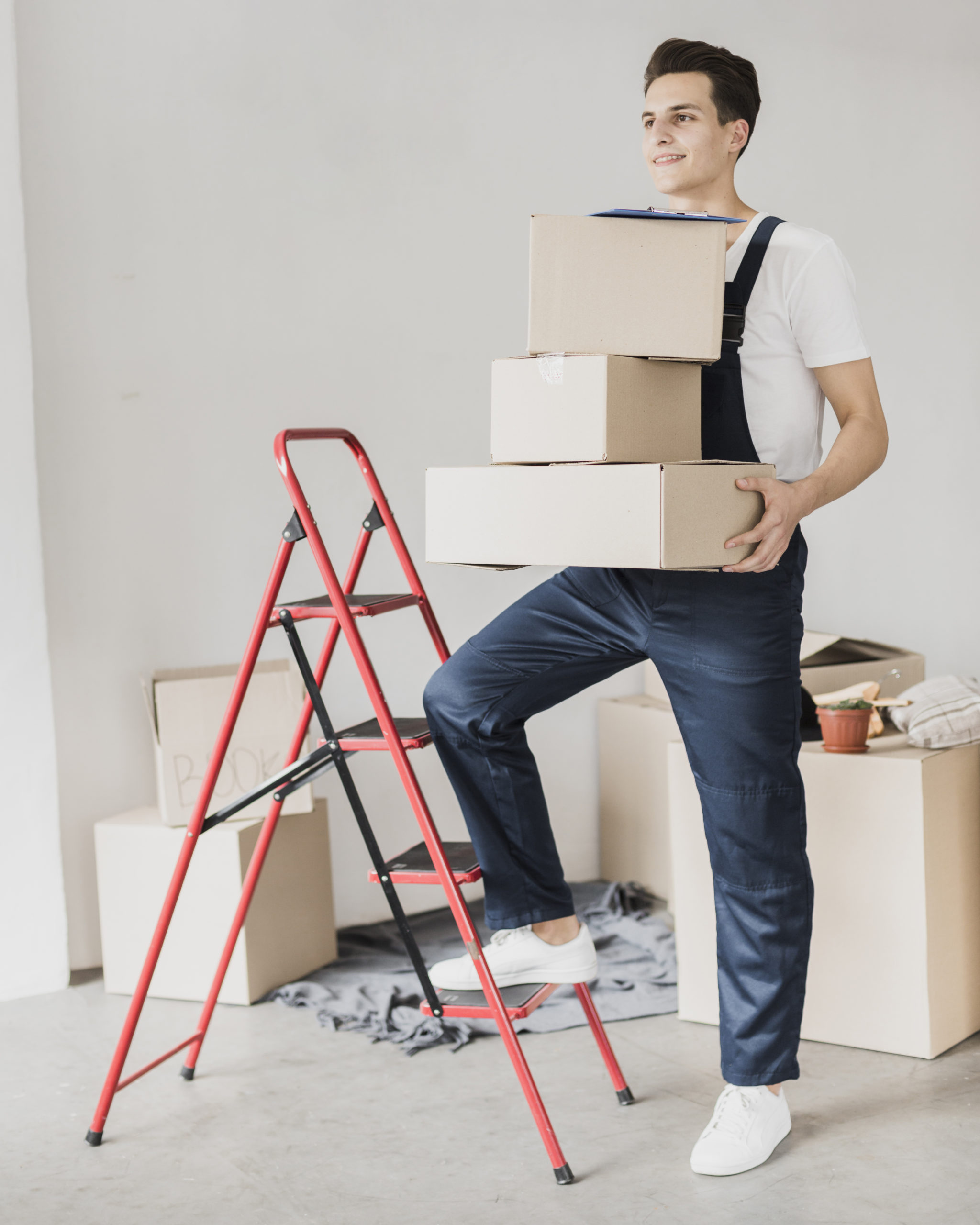 Young man holding boxes with a ladder nearby